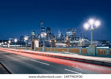 Light trail of car on bridge against illuminated urban skyline. London, United Kingdom