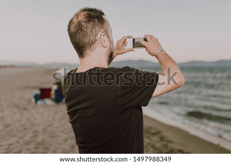 Man on the beach making a photo with his smartphone