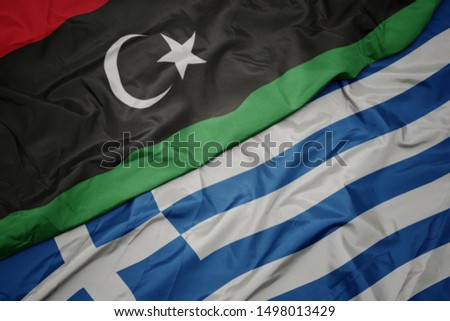 waving colorful flag of greece and national flag of libya. macro