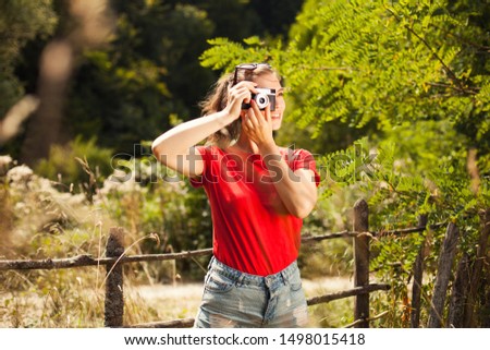 Pretty caucasian brunette woman taking a photo of a landscape with an analogue camera, summer or autumn outdoor nature holiday concept 