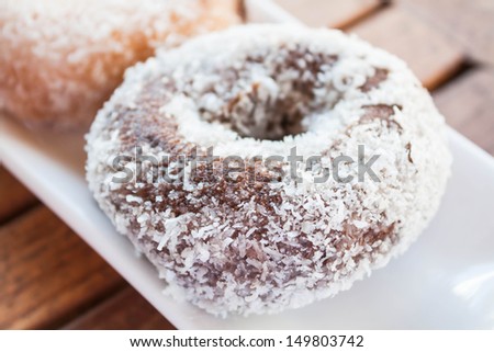 Close up chocolate coconut donut on white plate, stock photo