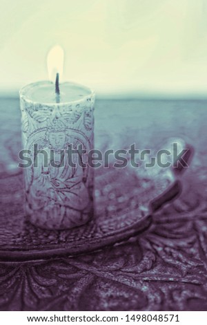 A lit buddha candle burning in an altar setting. Color processed art photography. 