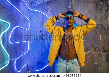 Black rapper in underpass neon light on background