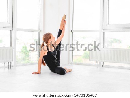Young beatiful dancer is showing her flexibility in white dancing room