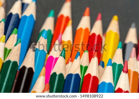 Close-up of colored sharpened pencils lie on each other on the table of an artist or a child. The concept of creativity and drawing