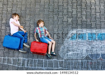 Two little kids boys having fun with train picture drawing with colorful chalks on ground