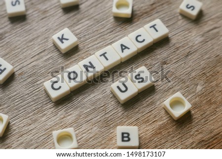 Business and finance concept. Contact Us alphabet square on wooden background. 