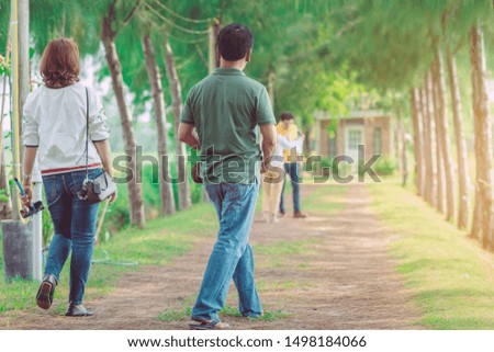 Couple walking and taking photos under the pine trees in the public park.