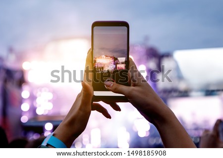 A girl is taking pictures of a street concert on the phone