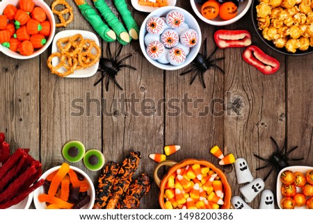 Halloween candy double border over a rustic wood background with copy space. Assortment of fun, spooky treats. Top view. Buffet party food concept.