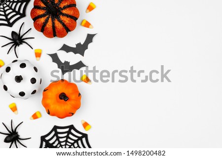 Halloween side border of pumpkins, candy and decor. Flat lay over a white background with copy space.