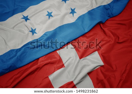 waving colorful flag of switzerland and national flag of honduras. macro