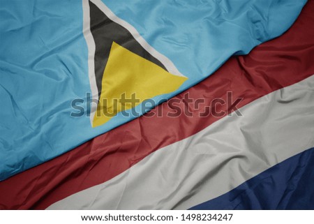 waving colorful flag of netherlands and national flag of saint lucia. macro