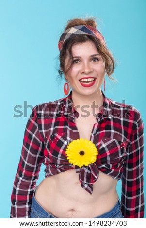 Vintage, fashion and floristic concept - woman with yellow flower in retro style on blue background