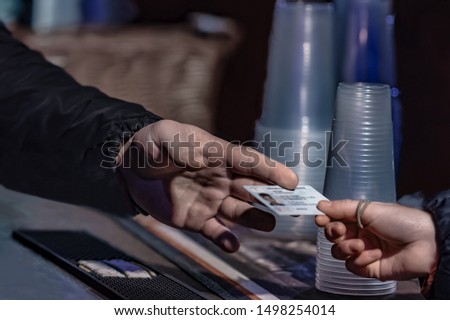 Young man show valid ID to buy alcohol and cigarettes in pub photographed with shallow depth of field Royalty-Free Stock Photo #1498254014