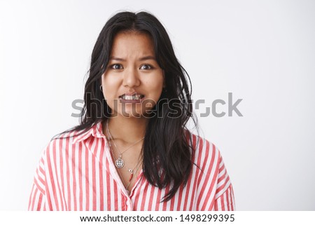 Yikes I am in trouble. Portrait of worried insecure and troubled cute female coworker making huge mess at work clenching teeth awkward and sorry admitting fault saying oops over white background Royalty-Free Stock Photo #1498299395