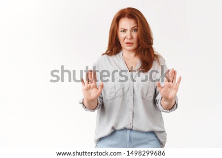Stop enough. Middle-aged good-looking redhead woman show no forbid gesture raise hands block defensive cringing raise eyebrow confused stare disdain disappointment refusing suspicious doubtful offer Royalty-Free Stock Photo #1498299686