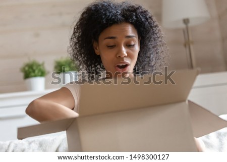 Frustrated african American millennial woman open cardboard box feel disappointed by wrong order, confused biracial female client unbox post package, receive poor quality product, bad service concept Royalty-Free Stock Photo #1498300127