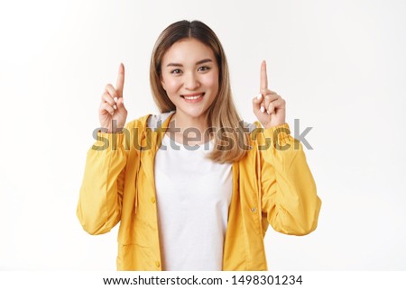 Girl offer great price product. Attractive cheerful smiling asian happy blond woman raise hands pointing up index finger introduce promo cheerfully propose you best choice white background
