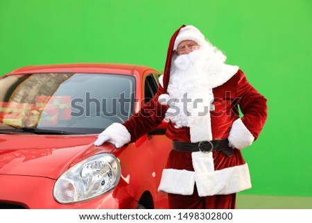 Authentic Santa Claus near car with presents against green background