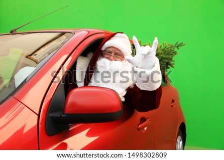 Authentic Santa Claus with fir tree driving car against green background