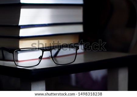 Stack of books and glasses closeup in the dark