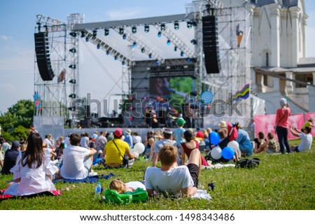 Couple watching concert at open air music festival, back view, stage and spectators at background