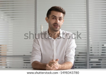 Young confident businessman looking at camera, talking to client. Concentrated male hr manager holding video distant job interview. Professional tutor recording educational vlog lecture, webcam view. Royalty-Free Stock Photo #1498343780
