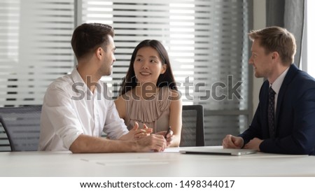 Smiling chinese young woman holding husbands hand, discussing house purchase, family savings investment. bank loan, mortgage, meeting bank manager, real estate agent, financial advisor at office.