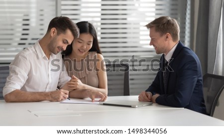 Happy young mixed race married spouse made decision about family savings investment, bank loan, mortgage or house purchase, buying consulting services, signing contract with bank manager in office.