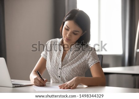 Concentrated young asian business woman leader working with financial reports, signing important documents, contract or agreement. Focused company executive manager making deal with corporate client. Royalty-Free Stock Photo #1498344329