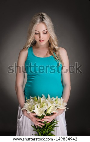 young pregnant woman with flowers on dark background