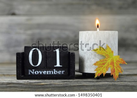 All Saints Day. Burning candle, wooden calendar and yellow autumn leaf Royalty-Free Stock Photo #1498350401