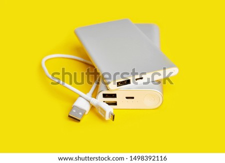 Power bank for charging mobile devices. White smart phone charger with power bank. Battery bank on a yellow background . External battery for mobile devices.