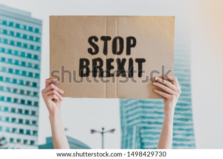 The phrase " Stop Brexit " drawn on a carton banner in men's hand. Human holds a cardboard with an inscription: Stop Brexit. Protest