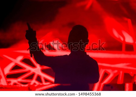 Silhouette of Dj with hands up playing at electronic party.