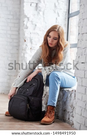 Young female photographer unpacking bag with equipment in photo studio