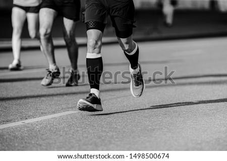 legs athlete runner in compression socks running street black and white photo
