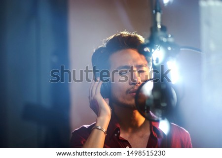 young asian musician singer singing song in recording studio