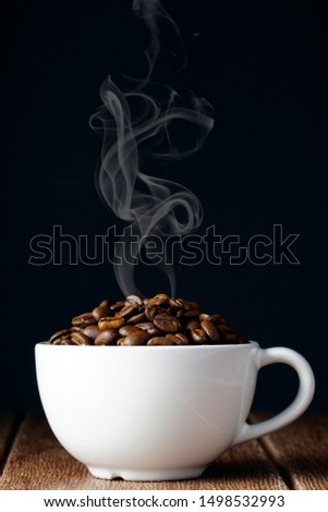 coffee beans in a white cup over wooden surface