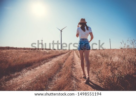 Windmills. Girl going to the wind turbines to take photos with it. They are located in the steppe in an open area.