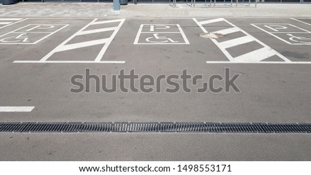 International handicap symbol in a parking lot of a shopping center. The space is clearly indicated on both sides by additional white diagonal stripes