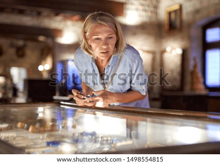 woman visitor in the historical museum looking at art object