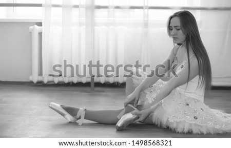 Young ballet dancer on a warm-up. The ballerina is preparing to perform in the studio. A girl in ballet clothes and shoes kneads by handrails.
