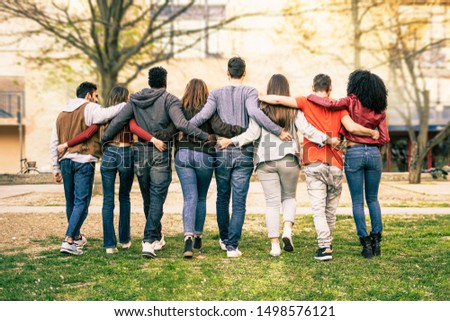 Group of young multiracial people walking arm around shoulders outdoors in a park. Students living enjoying diversity lifestyle concept. Royalty-Free Stock Photo #1498576121