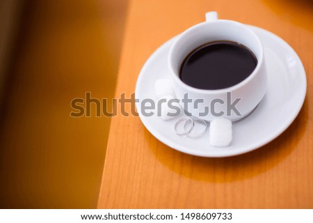 wedding rings with a cup of coffee and pieces of sugar