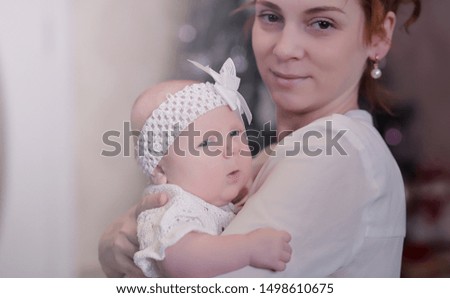 Mom with a newborn baby in her arms. The girl is holding a baby in front of the window. Newborn on mother hands.
