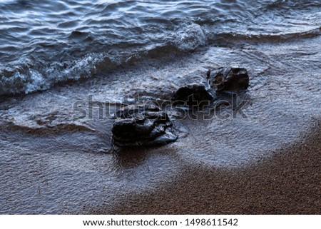 Dark photo coastal waves closeup. Rocks on the beach. Wet sand.