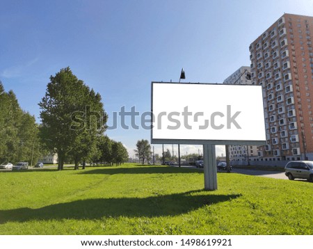 large billboard advertising in the city on a green lawn and against a blue sky