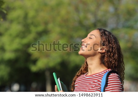 Happy mixed race student breathing deeply fresh air standing in a park or campus Royalty-Free Stock Photo #1498623911